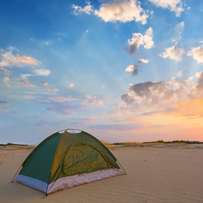 small green touristic tent stay among sandy desert at the evening