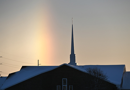 Winter rainbow behind church building.