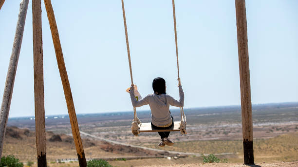 istock a woman swinging  in a desert 2086449404