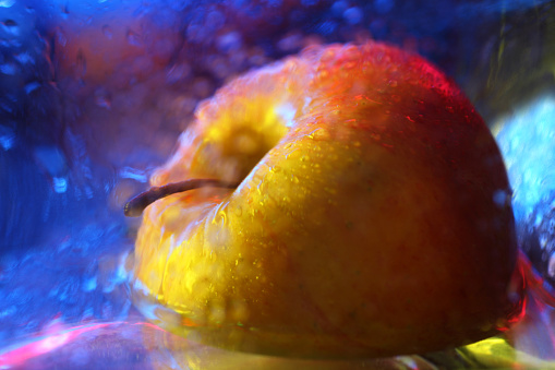 Wet apple in abstract lighting.