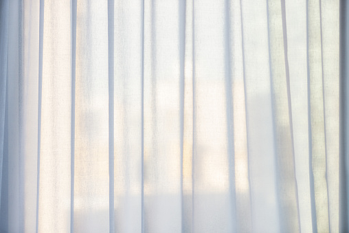 Morning light illuminating net curtains in a hotel room, providing privacy in the city center.