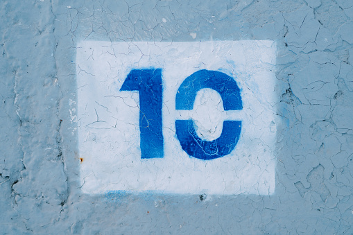 Number ten drawn in a white rectangle on a blue wall. High quality photo
