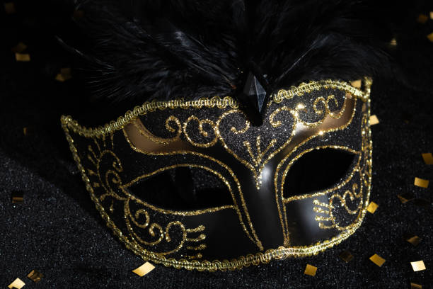 Bangkok, Thailand - 17 Sep, 2024 - Beautiful mysterious venetian mask with Feathers design and Silver round mirror on black background, Light and Shadow, Copy space. Selective Focus.