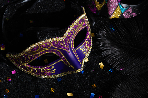 Carnival mask with confetties on black background.