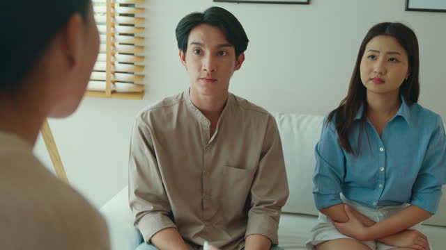 Close-up of Asian female psychotherapist advising couple after consult about mental health and relationship. Professional social worker assist married couples with empathy.