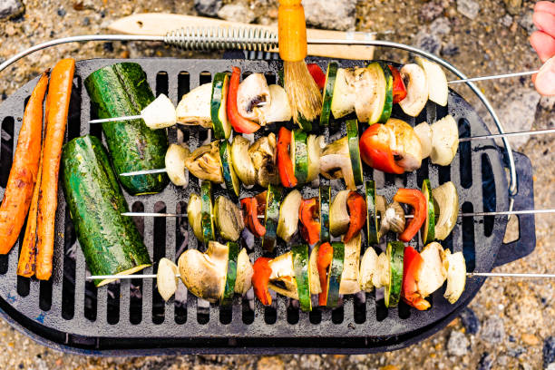 Assorted delicious grilled vegetable skewers on barbecue grill. Barbeque dinner outdoor, summer food.