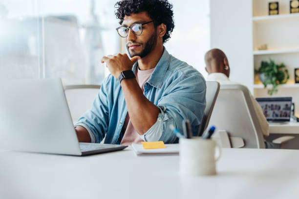 istock Focused young man working at laptop in bright office 2086533730