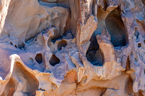 Closeup of a rock formation wall with holes, grooves, erosions and irregular texture, caused by passage of time, sunny day in Cerro de la Calavera, La Paz, Baja California Sur Mexico