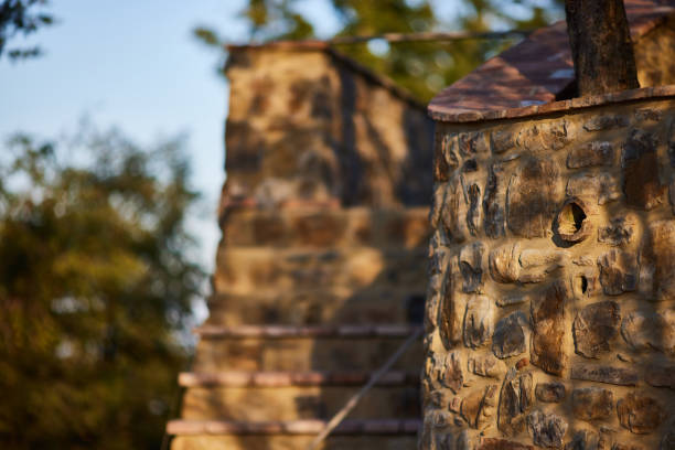 Sunlight and shadow falling on old fountain on textured stone retaining wall at Chiusdino