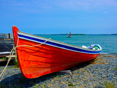 Red canoe moored on the rock beach in Boston, Massachusetts, a tranquil seascape in New England, USA