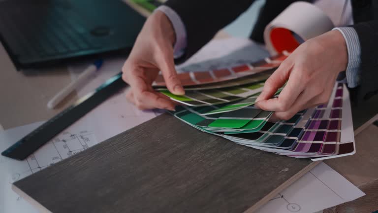 Person examining color palette next to laptop on table