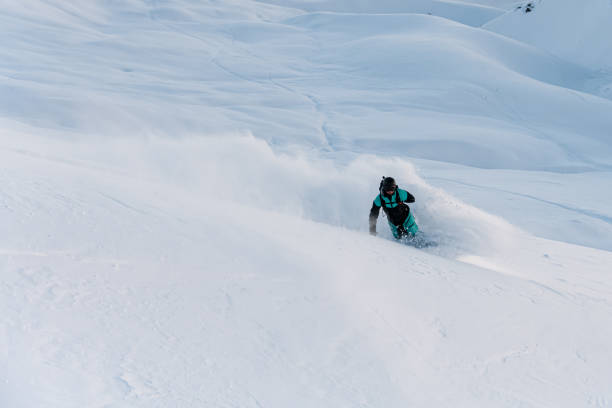 istock One-armed male snowboarder going down a snowy slope, on a snowboard 2086681097