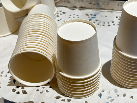 A stack of paper cups with a lace doily underneath. The cups are white and arranged in a neat stack