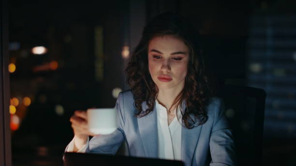 istock Late worker drinking coffee on dark workplace looking laptop screen close up. 2086706768