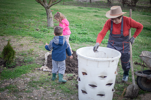 Gardening, a woman with her grandchildren prepares the soil for planting