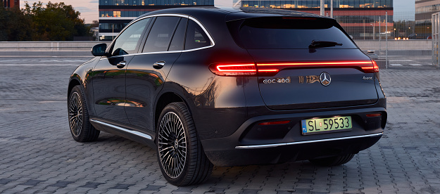 The all-electric Mercedes EQC sports SUV in the parking lot at sunset. Modern office buildings in the background. The car has a power of 408KM. Range (WLTP) 369-414 km. Katowice, Poland, June 10, 2020