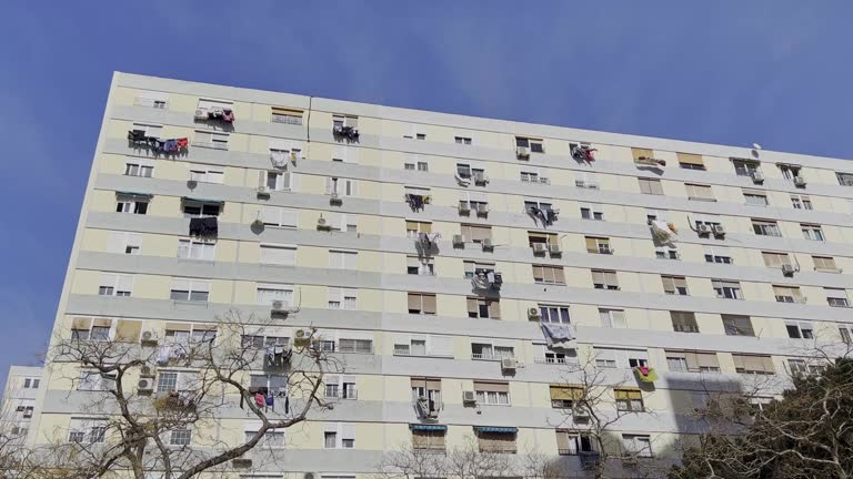 An exterior of a big white flat in Barcelona, people are drying their clothes