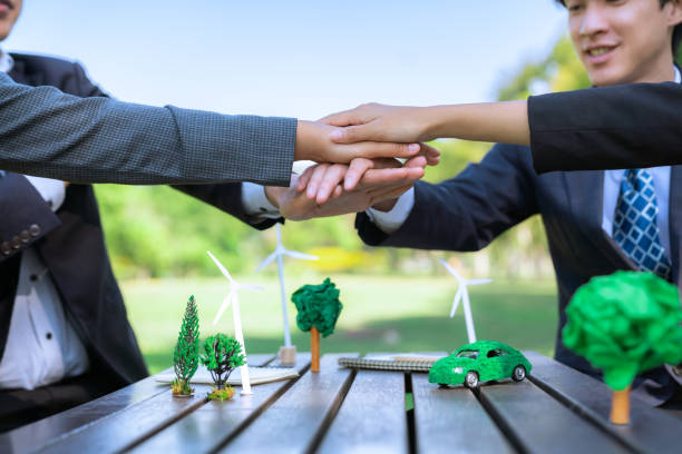 Business people join hand together as teamwork and unity, outdoor business meeting table. Eco-friendly practices and collaboration in corporate social responsibility for greener environment. Gyre