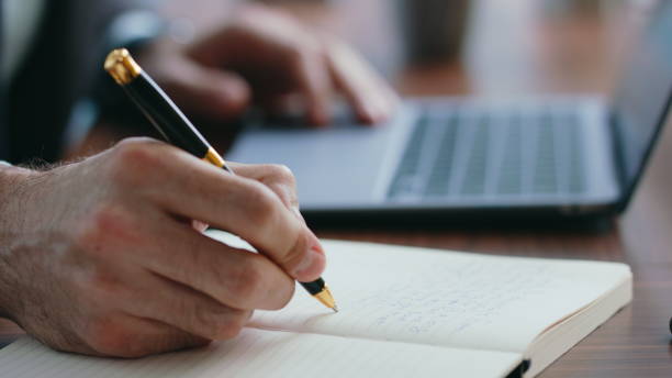 istock Boss hands noting information in notebook working on laptop close up. Man typing 2086760184