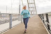 Overweight young woman exercising on bridge