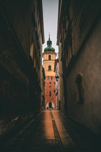 A tall tower stands at the end of a lengthy street surrounded by buildings
