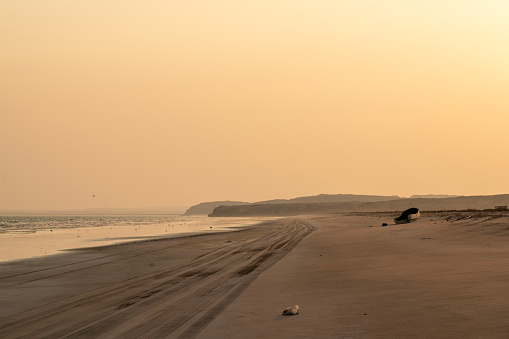 Beach at Al Khaluf at sunset, small boat left on the sandy beach, Arabian sea, south of Oman.