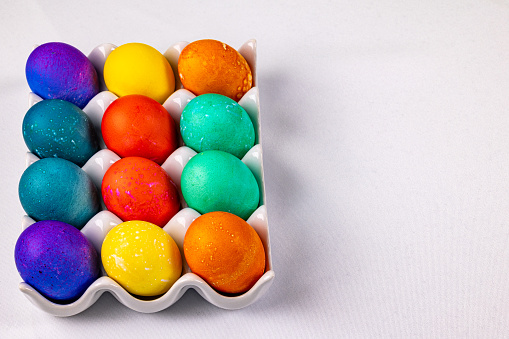 A dozen colored Easter eggs in a white ceramic dish with room for copy on the right side