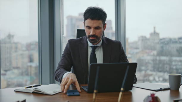 istock Smiling businessman answering call working on laptop at modern workplace closeup 2086835936