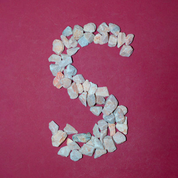 Letter S made of white stones. Creative alphabet concept on a red background.