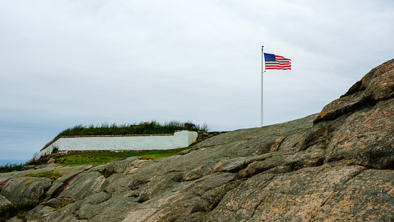 American flag waving over the rocks at Fort Taber Park in New Bedford,  Massachusetts, USA