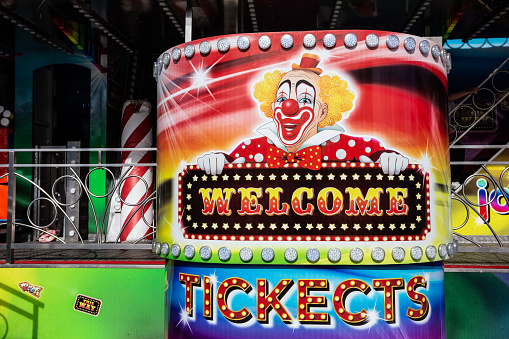 Man in a clown mask and a business suit. Isolated on a green background. The gesture of rubbing your hands. Halloween.