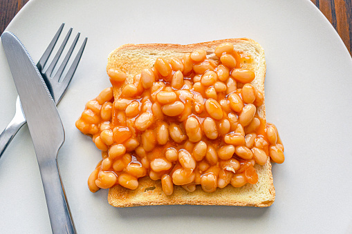 Beans on toast with fork and knife on a plate.