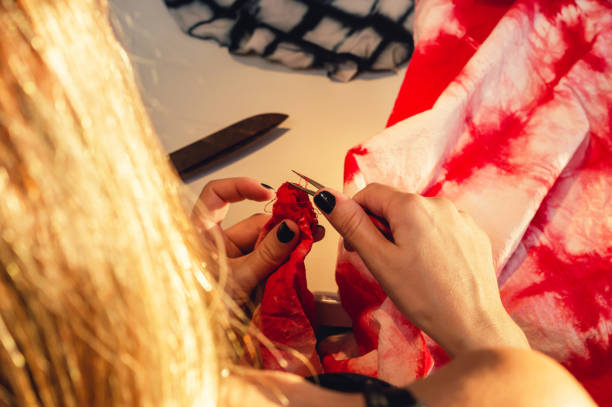 close-up of seamstress woman with a scissors cutting a thread on a red fabric - contreras zdjęcia i obrazy z banku zdjęć