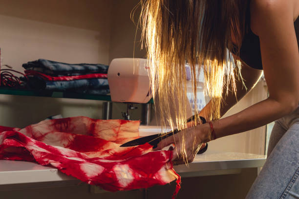 adult woman in her workshop cutting a red fabric with black steel scissors - contreras zdjęcia i obrazy z banku zdjęć