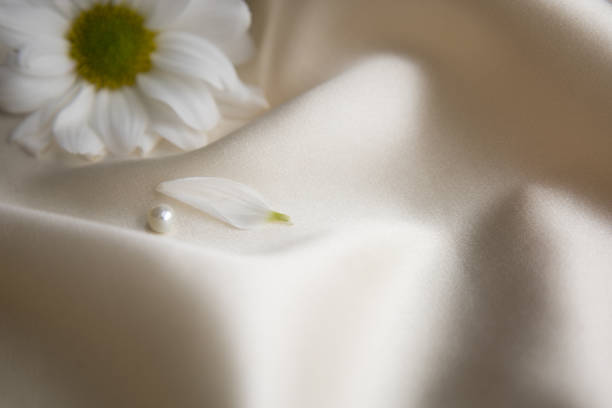 White chrysanthemum and pearls on silk background with space for message