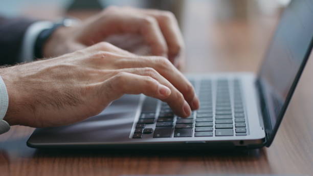istock Closeup man hands typing laptop keyboard taking smartphone from office desk. 2086944452