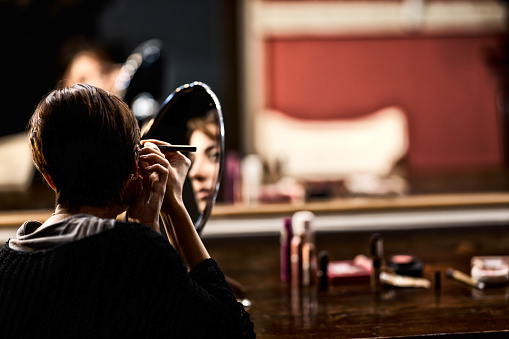 Young dancer/actress putting on makeup backstage to perform