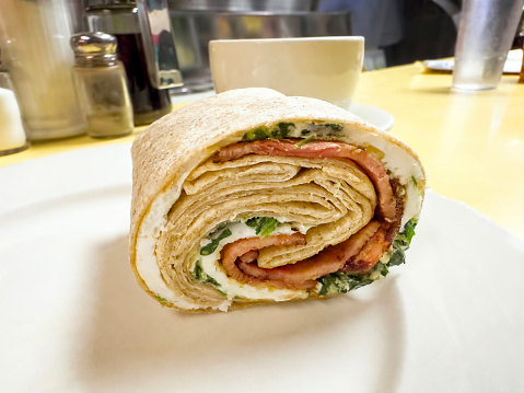 Close up breakfast wrap on a diner table with coffee cup