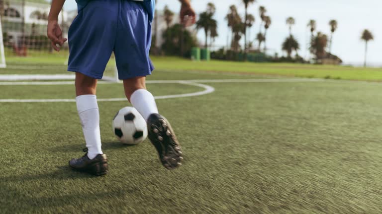 Goal, ball and feet of soccer child shooting practice for competition match, target aim or youth workout drill. Football player, running athlete and shoes of kid training strike power on grass pitch