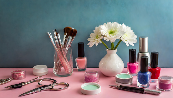 Decorative set of cosmetic, make-up and manicure products on a pink tablet with copy space