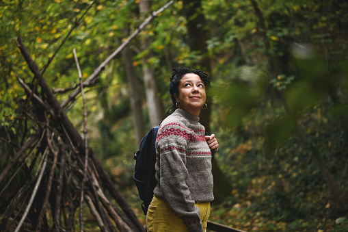 Mid adult Brazilian woman exploring forest in autumn.