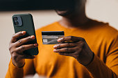 Man in Orange Sweater Holding Credit Card and Smartphone