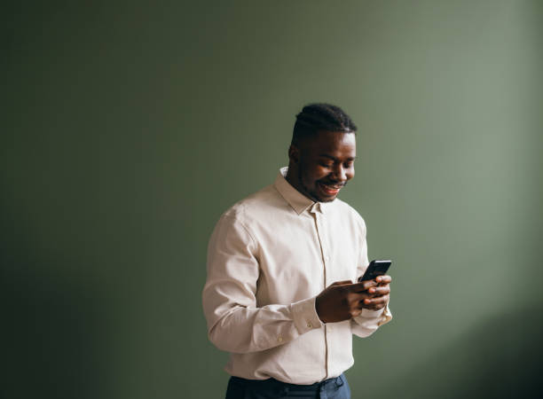 istock Smiling Businessman Using Smartphone on Green Background 2087154415