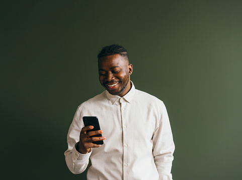 Joyful male texting happily on mobile phone, modern lifestyle.