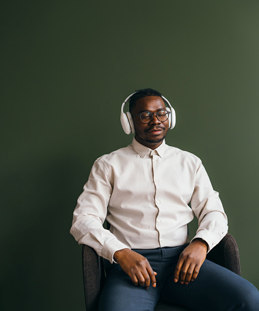 Content African-American man listening to music in office attire