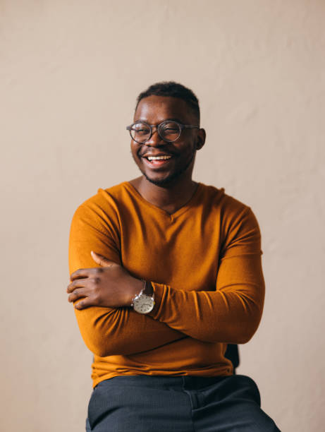 istock Cheerful Young Man with Glasses Smiling in Orange Sweater 2087154875