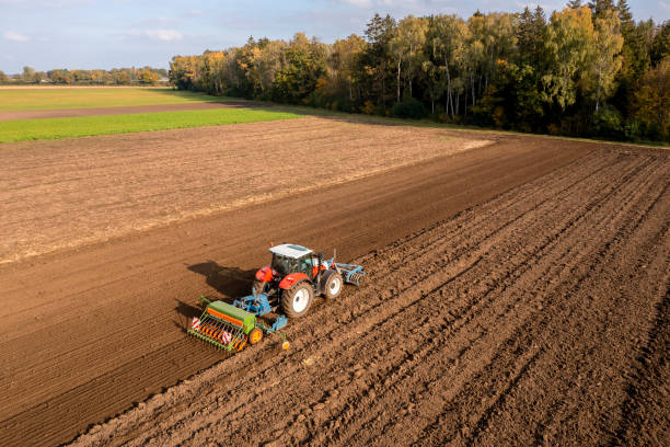 istock Red tractor sowing plowed field 2087168851