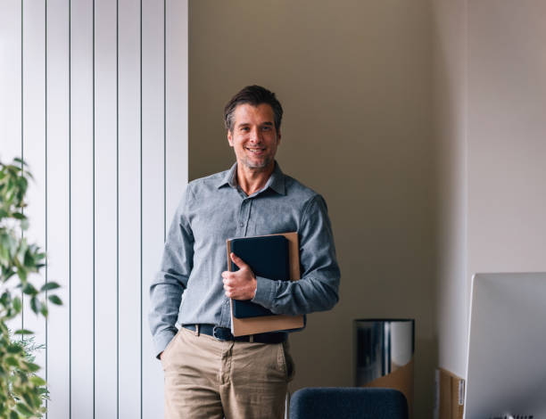 istock Smiling Businessman in Office Environment Holding Documents 2087206037