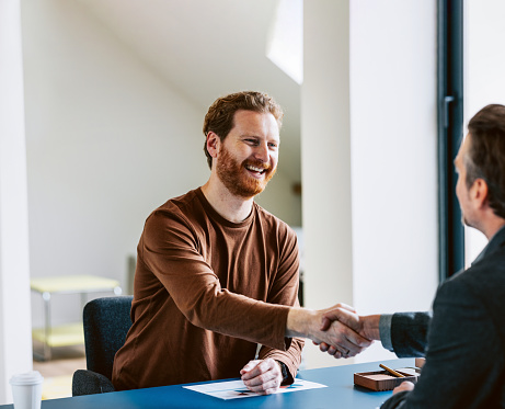 Cheerful bearded man shaking hands with colleague in a bright office setting