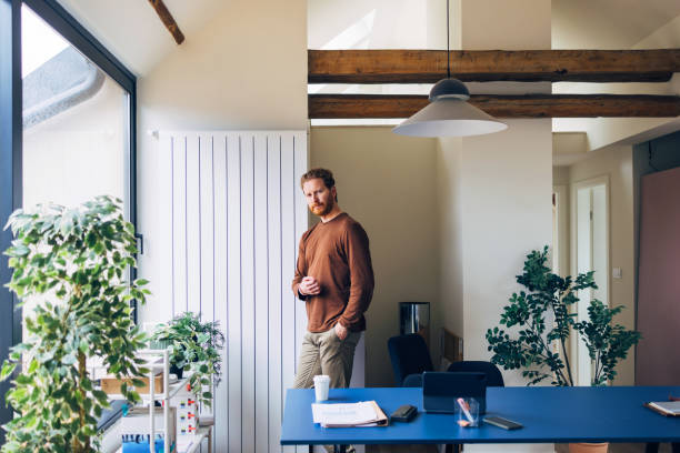 istock Contemplative Man Standing Alone in a Stylish Modern Office 2087206659